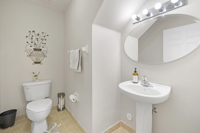 half bathroom featuring a sink, tile patterned floors, and toilet