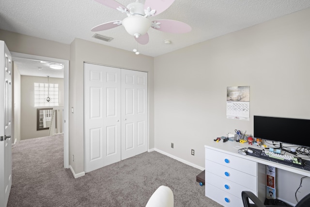 unfurnished office with carpet floors, a textured ceiling, and visible vents