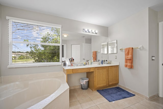 bathroom with tile patterned floors, baseboards, a garden tub, and vanity
