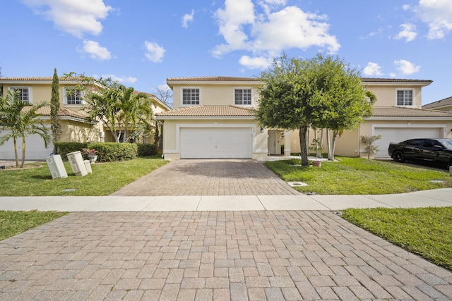 view of front facade with a tile roof, a front yard, decorative driveway, an attached garage, and stucco siding