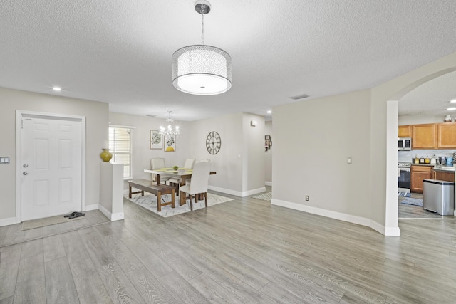 6427 Adriatic Way, Greenacres, FL 33413 - entrance foyer with a chandelier, a textured ceiling, light wood finished floors, arched walkways, and baseboards