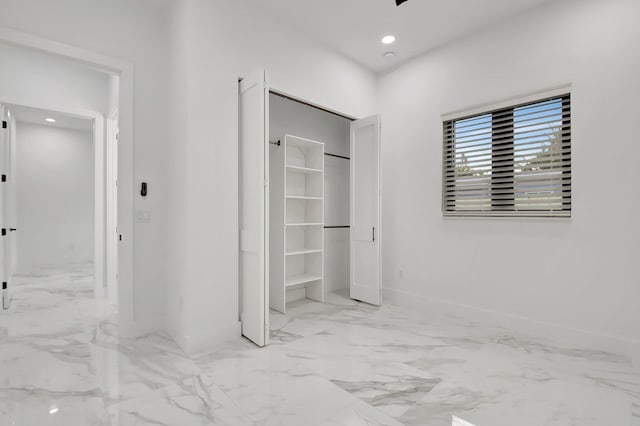unfurnished bedroom with recessed lighting, baseboards, marble finish floor, and a closet