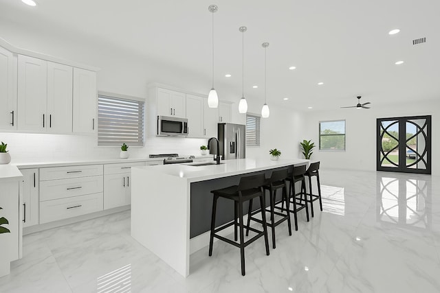 kitchen with visible vents, a center island with sink, a sink, marble finish floor, and stainless steel appliances