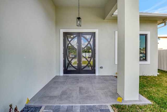doorway to property featuring fence, french doors, and stucco siding