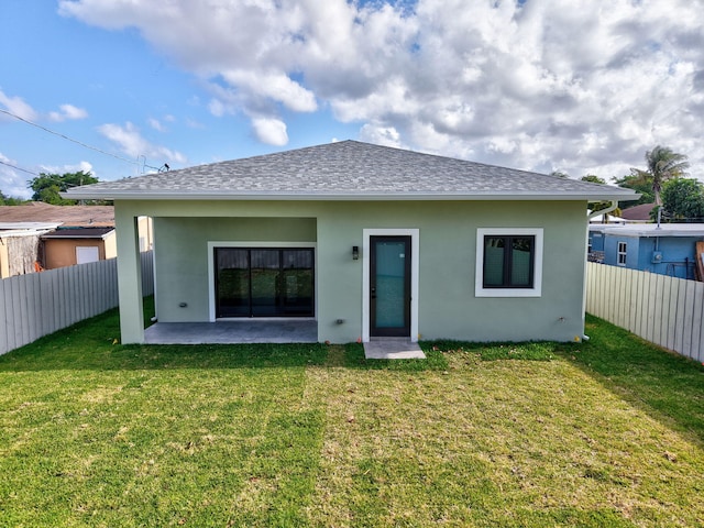 rear view of property with a fenced backyard, stucco siding, and a yard