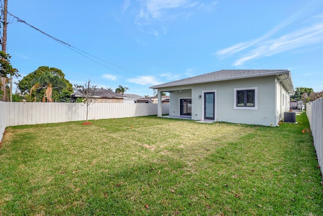 rear view of house with a fenced backyard, stucco siding, a lawn, and cooling unit
