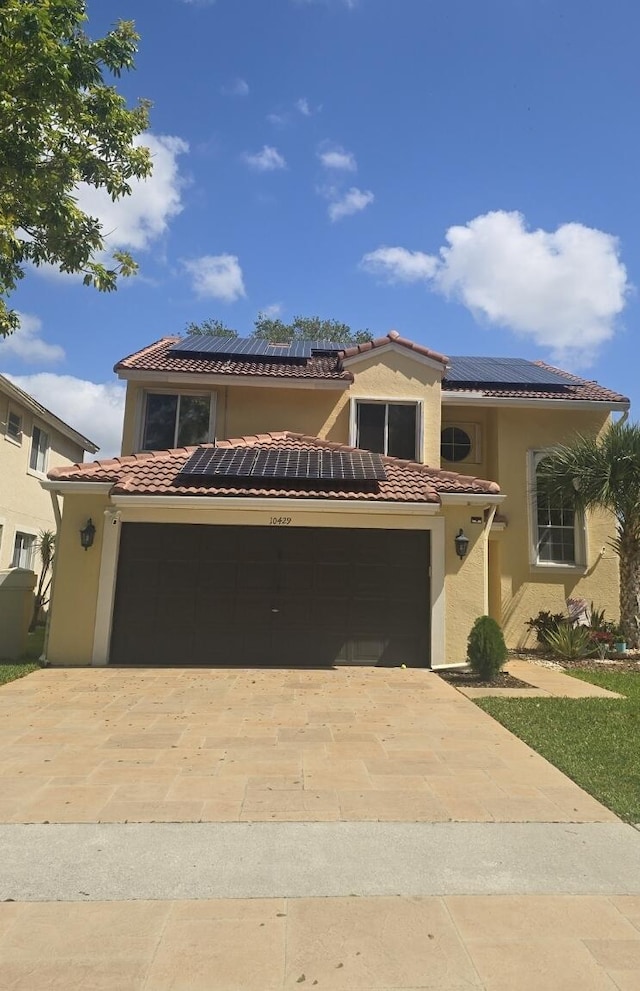 mediterranean / spanish house featuring driveway, solar panels, a tile roof, and stucco siding