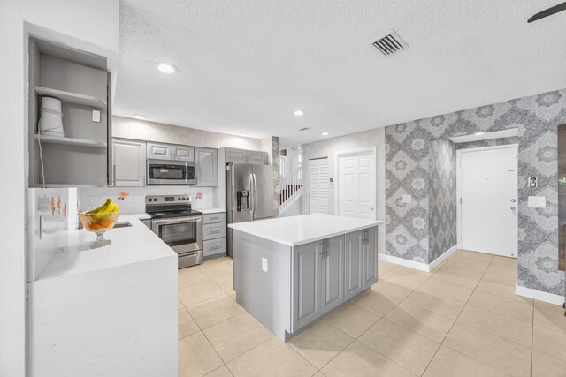 kitchen with wallpapered walls, visible vents, gray cabinetry, and stainless steel appliances