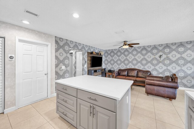 kitchen featuring ceiling fan, open floor plan, wallpapered walls, light tile patterned floors, and gray cabinetry