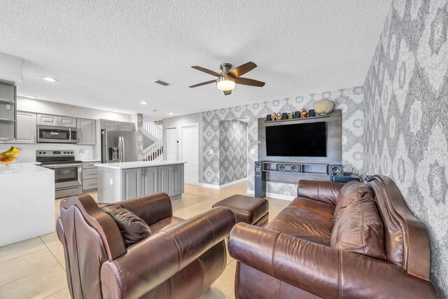 living area with visible vents, stairs, wallpapered walls, a textured ceiling, and a ceiling fan