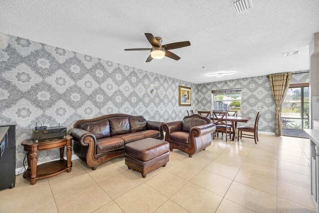 living room with visible vents, a ceiling fan, a textured ceiling, and wallpapered walls