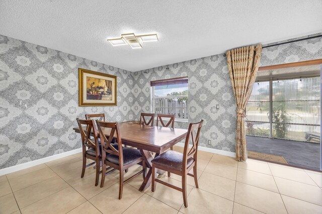 dining room featuring light tile patterned floors, baseboards, wallpapered walls, and a textured ceiling