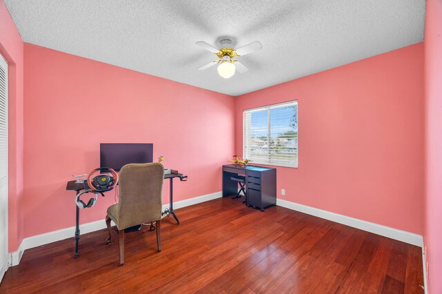 office featuring a ceiling fan, baseboards, wood finished floors, and a textured ceiling