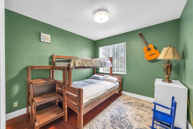 bedroom with baseboards, a textured ceiling, and wood finished floors