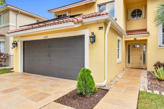 view of front of home with a tiled roof, a garage, driveway, and stucco siding
