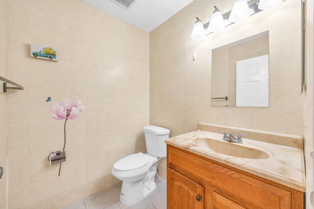 bathroom featuring vanity, visible vents, toilet, tile walls, and tile patterned floors