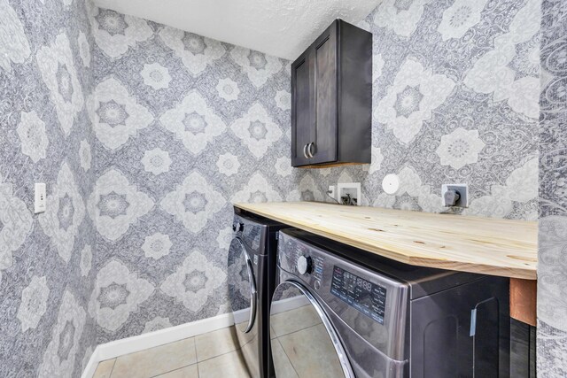 washroom with cabinet space, light tile patterned floors, baseboards, wallpapered walls, and washer and clothes dryer