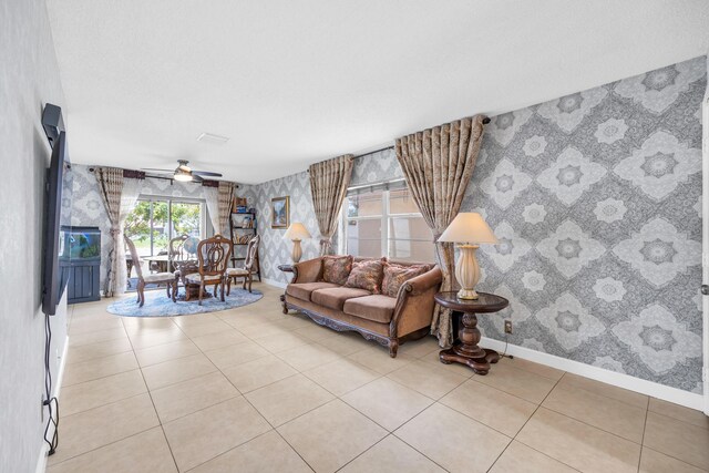 tiled living room with a ceiling fan, wallpapered walls, and baseboards
