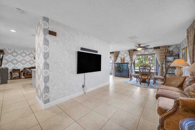 living area featuring baseboards, wallpapered walls, ceiling fan, and light tile patterned floors