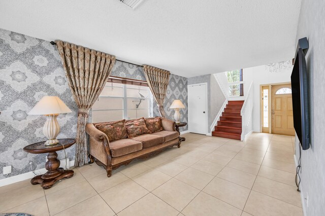 living area with stairway, baseboards, light tile patterned floors, and wallpapered walls
