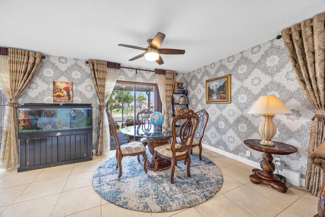 tiled dining space featuring baseboards, a ceiling fan, wallpapered walls, and a textured ceiling