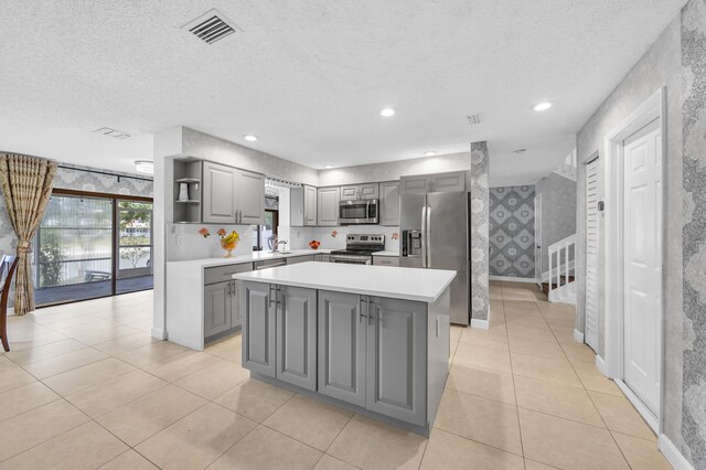 kitchen with open shelves, light countertops, gray cabinets, stainless steel appliances, and visible vents