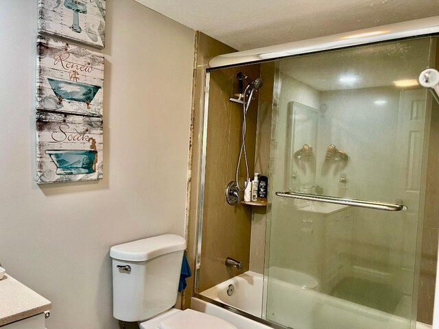 bathroom featuring vanity, combined bath / shower with glass door, and toilet