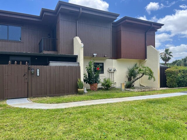 view of home's exterior featuring a yard, fence, a gate, and stucco siding
