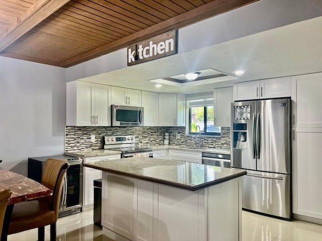 kitchen featuring wood ceiling, light stone counters, a sink, appliances with stainless steel finishes, and backsplash