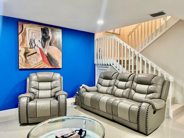 living room featuring visible vents, baseboards, and stairway