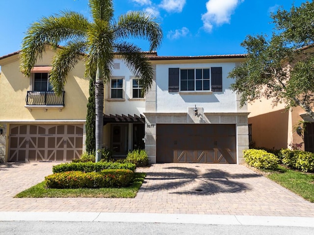 mediterranean / spanish home with an attached garage, decorative driveway, and stucco siding