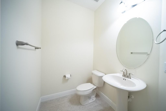 half bath with baseboards, toilet, and tile patterned flooring