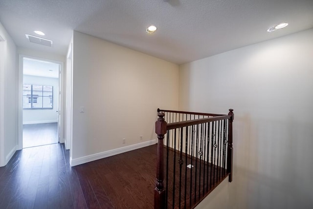 corridor with an upstairs landing, dark wood-style floors, baseboards, and recessed lighting