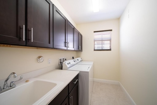 clothes washing area featuring cabinet space, washing machine and dryer, baseboards, and light tile patterned floors