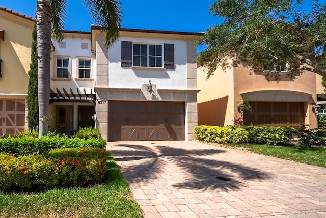 mediterranean / spanish house with a garage, decorative driveway, and stucco siding