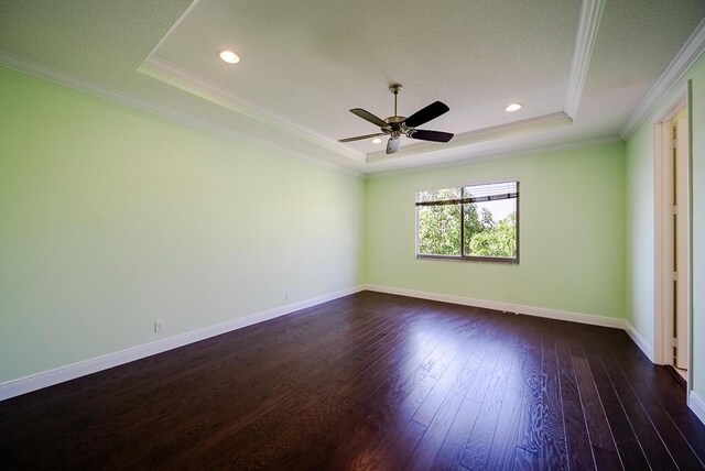 unfurnished bedroom with a raised ceiling, dark wood-style floors, crown molding, baseboards, and ceiling fan