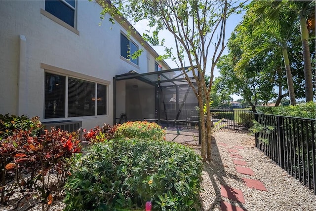 view of yard featuring fence, central AC, and a lanai