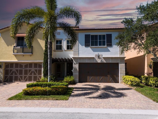 mediterranean / spanish-style house featuring a garage, decorative driveway, and stucco siding