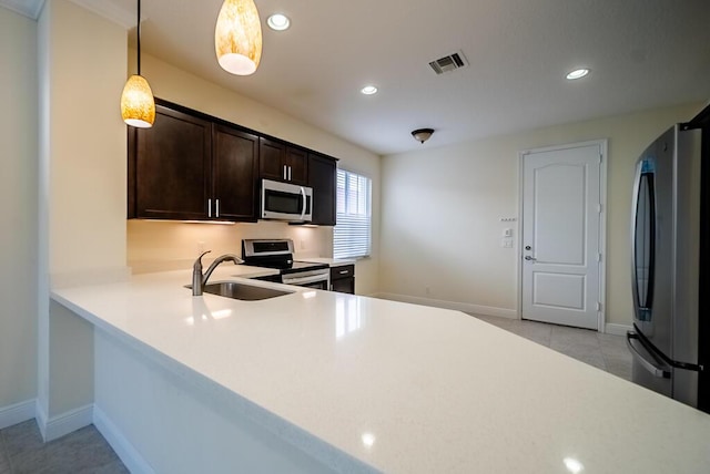 kitchen featuring stainless steel appliances, a sink, dark brown cabinetry, light countertops, and baseboards