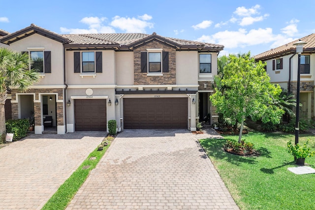 12968 Anthorne Ln, Boynton Beach, FL 33436 - view of property with a front yard, decorative driveway, stucco siding, a tiled roof, and an attached garage