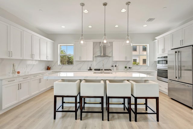 5285 Beckman Ter, Palm Beach Gardens, FL 33418 - kitchen with appliances with stainless steel finishes, wall chimney range hood, tasteful backsplash, a kitchen breakfast bar, and recessed lighting