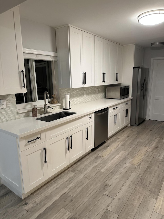 5111 NE 27th Ter NE, Lighthouse Point, FL 33064 - kitchen featuring appliances with stainless steel finishes, a sink, backsplash, light countertops, and light wood-type flooring