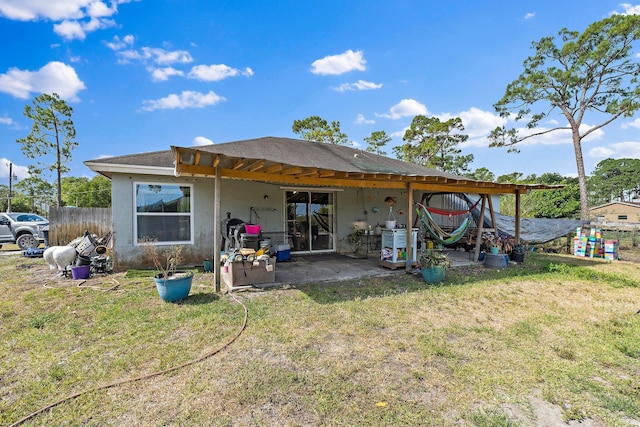 rear view of house featuring a yard, a patio, fence, and stucco siding