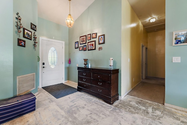 carpeted entrance foyer featuring a towering ceiling, baseboards, and visible vents