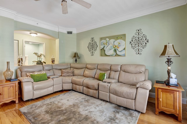 living area featuring arched walkways, ceiling fan, ornamental molding, and light wood-style flooring