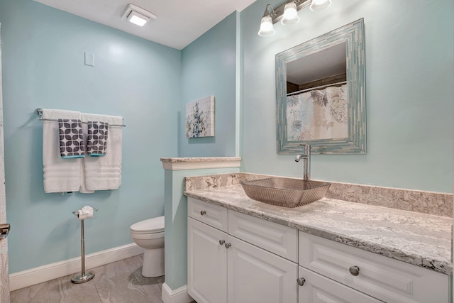 full bathroom featuring toilet, baseboards, marble finish floor, and vanity