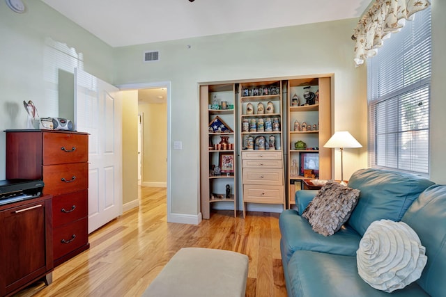 living area featuring visible vents, light wood finished floors, and baseboards
