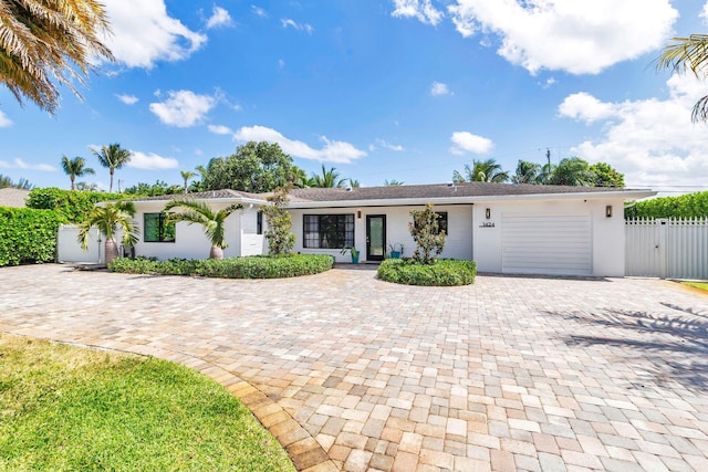 view of front of home featuring fence, decorative driveway, an attached garage, stucco siding, and a gate