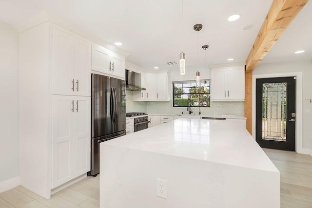 kitchen featuring tasteful backsplash, freestanding refrigerator, recessed lighting, wall chimney exhaust hood, and gas range