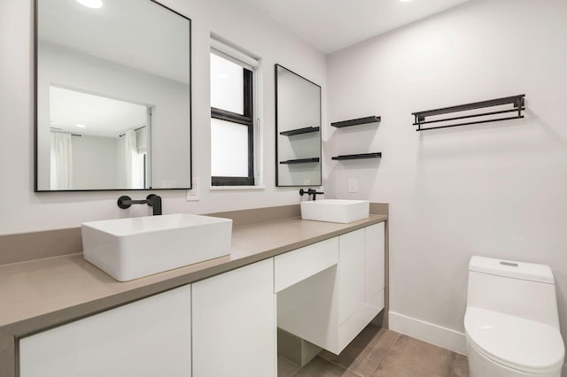 bathroom featuring a sink, double vanity, toilet, and recessed lighting